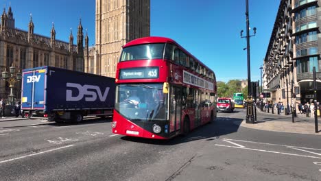 Double-decker-buses-traverse-Bridge-Street,-passing-the-Houses-of-Parliament-in-Westminster,-London,-illustrating-the-concept-of-iconic-urban-transportation-and-city-exploration