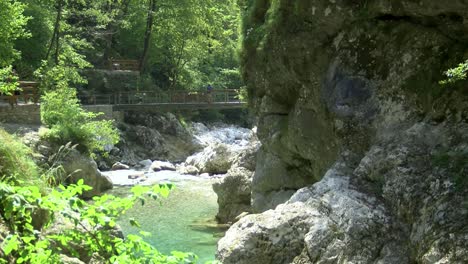 tourists-walking-across-bridge-in-tolminka-gorge-natural-landmark,-wide-static-shot