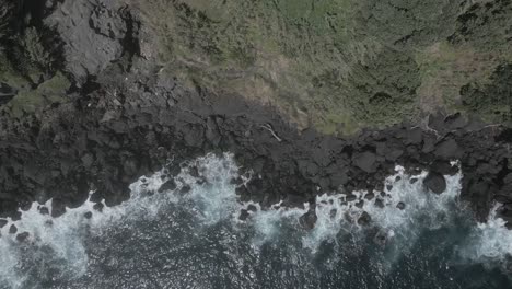 Waves-crashing-on-rocky-cliff.-Aerial-top-down-forward