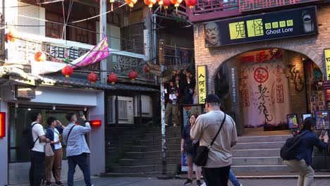 People-walking-down-the-Shuqi-road-next-to-the-building-of-Ghost-Lore-Museum-in-Jiufen-Old-Street,-popular-tourist-spot-nestled-in-Taiwan's-mountain-town