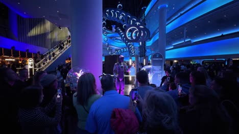 A-crowd-gathers-around-an-exhibit-taking-photos-in-dimly-lit-venue,-Las-Vegas