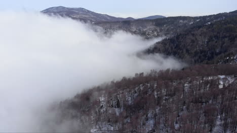 Luftaufnahme-Der-Wunderschönen-Berghänge,-Die-Mit-Schwebenden-Wolken-Im-Wald-Bedeckt-Sind,-Wintertag-In-Kaimaktsalan,-Griechenland
