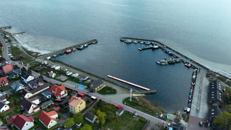 Aerial-view-of-the-Kuźnica-harbor-on-the-Baltic-coast,-featuring-docks,-moored-boats,-and-surrounding-residential-areas,-capturing-the-quaint-and-vibrant-maritime-life