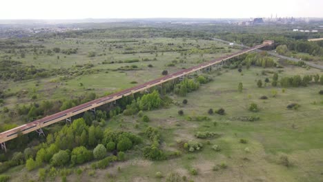 Very-long-over-ground-elevated-tunnel-going-over-a-field-and-leading-to-a-far-away-factory