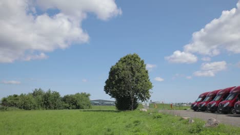 Geparkte-Lieferwagen-Von-HSM-Global-In-Der-Nähe-Der-Landebahn-Des-Flughafens,-Während-Das-Flugzeug-Abhebt