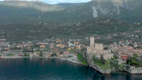 View-of-Malcesine-Castle-fortress-and-rocky-cliffs-in-Lake-Garda,-featuring-medieval-architecture,-town-rooftops,-Italy