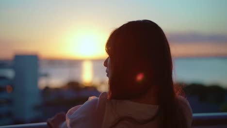 Woman-looking-out-to-sea-on-the-cruise-in-the-evening-sunset-back-shot-slow