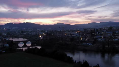 Die-Dämmerung-Bricht-über-Barcelos-Herein-Und-Präsentiert-Einen-Ruhigen-Fluss-Und-Eine-Historische-Brücke,-Umrahmt-Von-Einem-Pastellfarbenen-Himmel