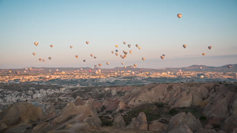 Dawn-breaks-over-Cappadocia-as-multiple-hot-air-balloons-dot-the-sky,-timelapse-capture-of-scenic-landscape