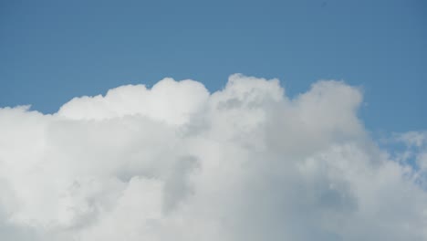 Fluffy-white-clouds-move-swiftly-across-a-bright-blue-sky-in-a-timelapse