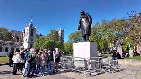 Grupo-De-Turistas-De-Pie-Junto-A-La-Estatua-De-Winston-Churchill-En-La-Plaza-Del-Parlamento-En-Un-Día-Soleado-Por-La-Mañana