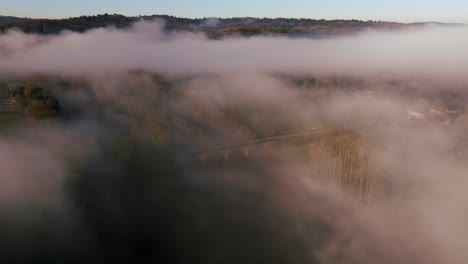 Stone-bridge-in-the-mist,-drone-view-at-sunrise-in-Périgord---France