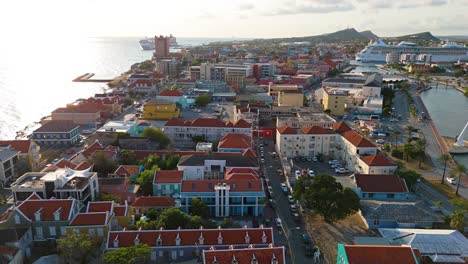 Panoramic-aerial-dolly-above-orange-iconic-world-heritage-roofs-of-Curacao-at-sunset