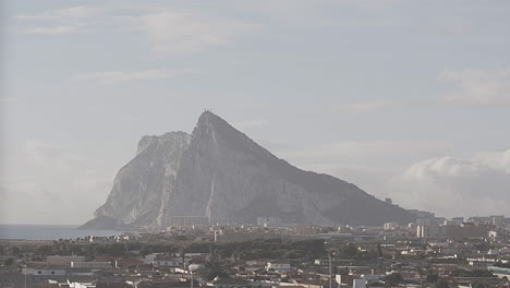 A-Timelapse-photography-from-Spain,-of-clouds-passing-by-the-rock-of-Gibraltar-around-sunrise-as-the-sun-is-hitting-the-north-east-face-of-Gibraltar's-Rock