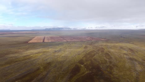 Aerial-shot-of-Iceland's-vast,-colorful-terrain-with-patchwork-fields-under-a-cloudy-sky,-showcasing-nature's-palette