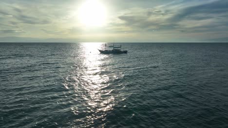 Drone-approaching-shot-of-beautiful-seascape-and-boat-with-sun-reflects-on-water-surface