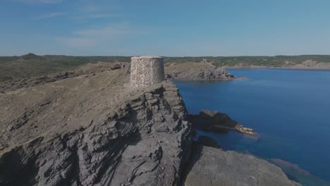 Torre-D&#39;es-Colomer-Blau-Mittelmeer-Skyline-Drohne-Fliegen-Menorca-Felsiger-Strand-Steinturm-Aussichtspunkt