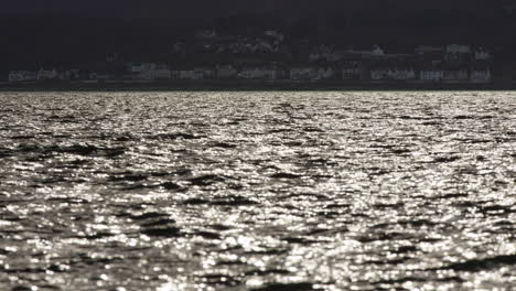 Shimmering-water-reflects-bright-midday-light-below-row-of-townhomes