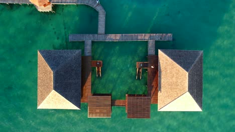 Aerial-birds-eye-view-of-a-villa-with-a-wooden-pier-in-the-middle-of-crystal-clear-water-at-Leebong-Island,-Belitung-Indonesia