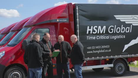 HSM-Global-delivery-van-drivers-in-group-discuss-logistical-admin-next-to-vans