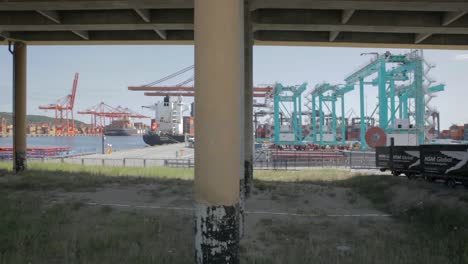 HSM-Global-fleet-of-delivery-vans-lined-up-under-bridge-near-port,-panning-shot