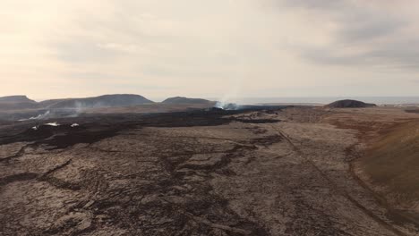 Desolate-volcanic-rock-wasteland-with-smoking-vents-and-volcano