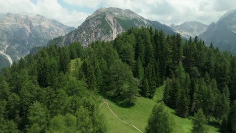 Aerial-footage-of-a-drone-flying-above-a-forest,-a-meadow-and-a-mountain-hut-in-the-area-of-Crucs-da-Rit-and-Utia-da-Rit-near-the-village-of-La-Val,-South-Tyrol,-Dolomites,-Italy