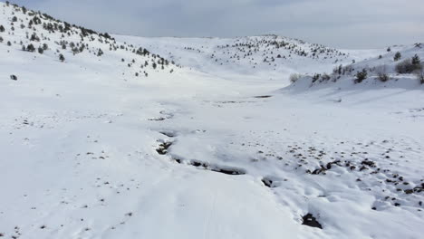 Aerial-view-of-beautiful-mountain-valley-covered-in-snow-mountain-peak-at-the-distance-winter-day