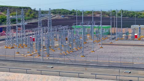 Power-Plant-Station-Construction-in-front-of-large-solar-panel-farm-park-on-Dominican-Republic