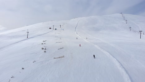 Drone-view-of-skiers-skiing-downhill-in-the-slopes-in-the-scenic-Mountain-Kaimaktsalan-Greece-winter-day