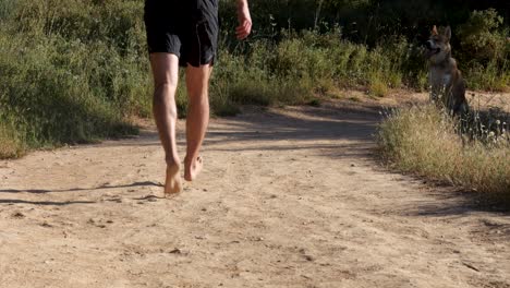 Shot-of-a-person-running-in-the-morning-on-a-city-forest-trail-with-his-dog