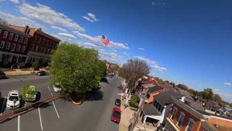 Plaza-De-La-Ciudad-Americana-Con-Bandera-De-EE.UU.-Y-Edificios-Pintorescos-En-Un-Brillante-Día-De-Primavera