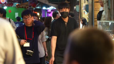 Los-Turistas-Deambulan-Por-Un-Encantador-Callejón-Lleno-De-Puestos-De-Comida-Y-Tiendas-De-Regalos-Dentro-De-La-Antigua-Calle-Jiufen,-Vendedores-Que-Reparten-Muestras,-Un-Popular-Lugar-Turístico-Ubicado-En-La-Ciudad-Montañosa-De-Taiwán.