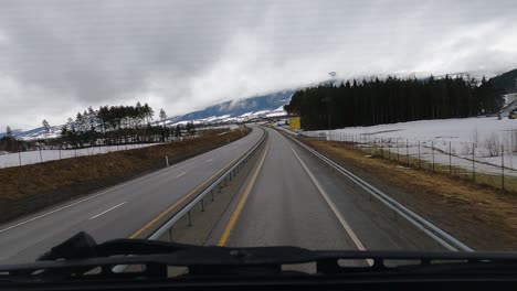Traveling-Scenic-Winter-Highway,-Passing-Under-Arc-Bridge-In-Norway
