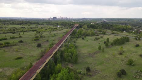 long-and-rusted-abandoned-structure-that-provides-supplies-to-a-factory-in-far-background-in-Poland-near-Katowice