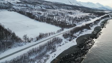 Drone-shot-of-Highway-in-Tromso-Norway-during-winter-with-snow-near-water