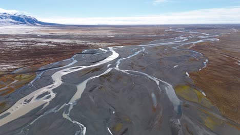 Glacier-plain-landscape-with-rivers-and-silt-mud-below-snowy-mountains