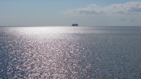 Silhouette-Eines-Kreuzfahrtschiffs,-Das-Am-Horizont-Segelt,-Während-Das-Wasser-In-Der-Sonne-Glitzert