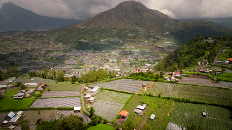 Panoramic-aerial-view-of-Balinese-farm-lands-and-iconic-Mount-Batur,-Bali