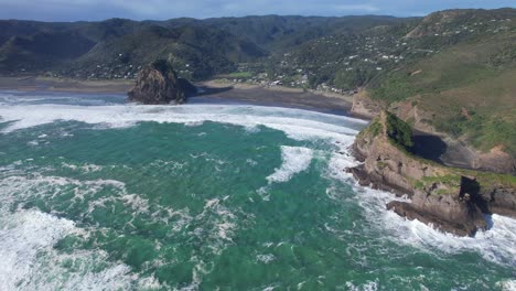 Piha-Sand-Black-Beach-Y-Pueblo-Costero-En-El-Parque-Regional-Waitakere-Ranges,-Región-De-Auckland,-Isla-Del-Norte,-Nueva-Zelanda