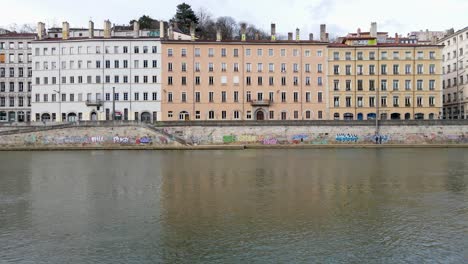 Colorful-buildings-and-graffiti-paintings-by-the-river-in-the-city-of-Lyon,-France