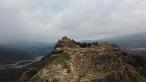 Ruinas-Antiguas-En-La-Cima-De-Una-Colina-En-Siurana,-Tarragona,-Con-Un-Paisaje-Montañoso-Como-Telón-De-Fondo,-Vista-Aérea