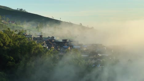 Pueblo-Brumoso-En-La-Ladera-De-La-Montaña-En-Indonesia,-Amanecer-Temprano-En-La-Mañana,-Vista-Aérea