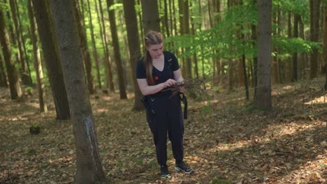 Mujer-Joven-Recoge-Palos-En-El-Bosque