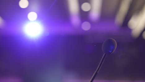 Microphone-close-up-with-vibrant-purple-stage-lighting-in-the-background,-shallow-focus