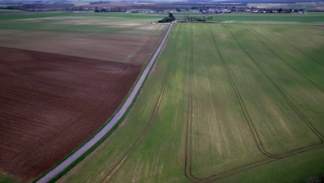 Drone-shot-over-a-road-and-fields,-graphic-shot-and-a-stormy-storm,-a-car-drives-by
