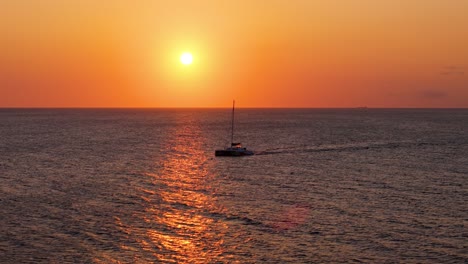 Catamaran-drives-across-open-clear-waters-passing-sunlight-plume-of-light-reflecting-on-sea