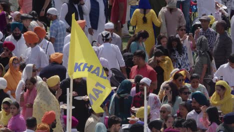 Sikh-Feiernde-Genießen-Gutes-Essen-Beim-Nagar-Kirtan,-Die-Khalistan-Flagge-Weht