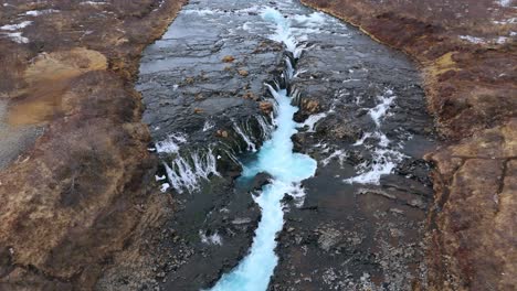 Bruarfoss-waterfall-in-iceland-with-vivid-blue-glacial-water,-aerial-view