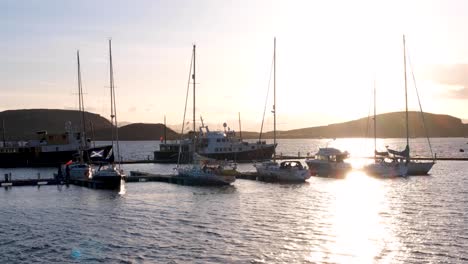 Schimmerndes-Licht-über-Dem-Meerwasser-Bei-Sonnenuntergang-Mit-Festgemachten-Booten-Und-Schiffen-Im-Hafen-In-Der-Stadt-Oban,-Westschottland,-Großbritannien
